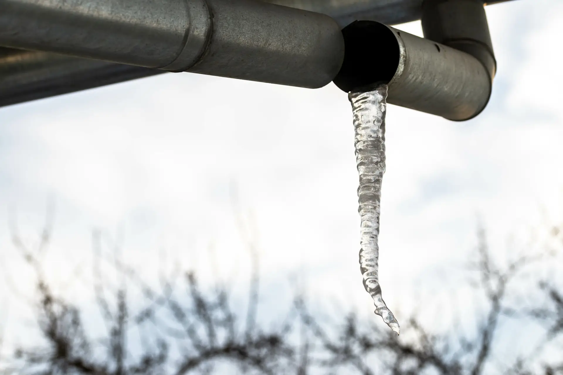 Ice on broken gutter on residential house at a cold winter day close up shot.